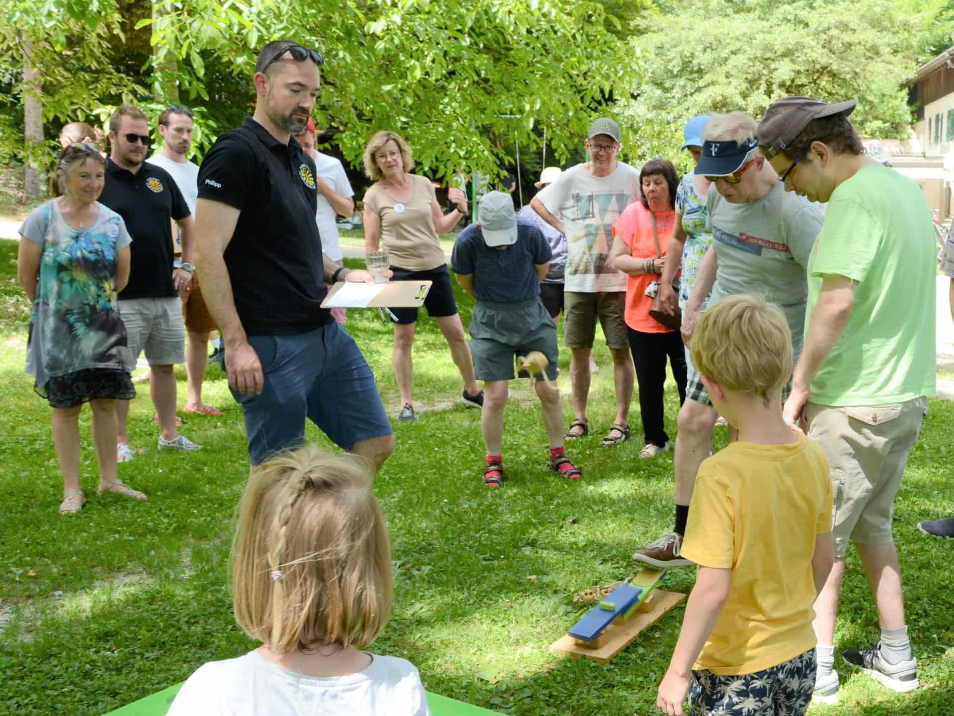 Gruppe beobachtet Kinder beim Holzspiel im Garten